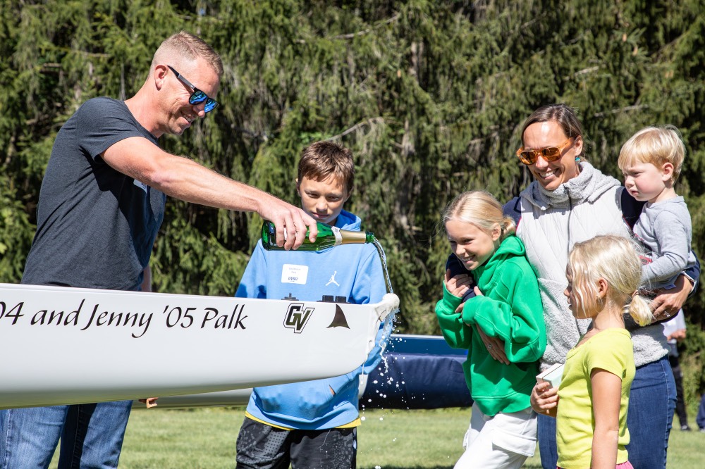 John Palk pours champagne on boat and family watches him